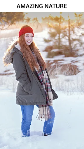 Winter nature background example showing woman in red winter hat and dark jacket with snowy background and golden field setting